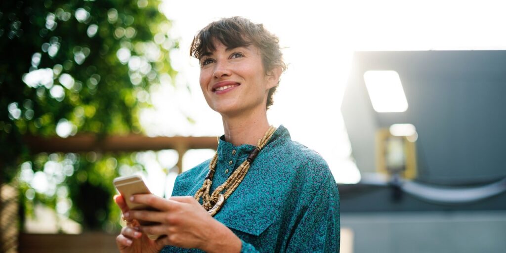 Smiling woman holding her phone while texting her dietitian on demand