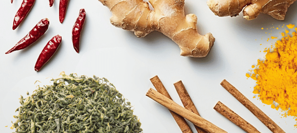 Photo of dried red peppers, fresh ginger, cinnamon sticks, dried green tea, and tumeric