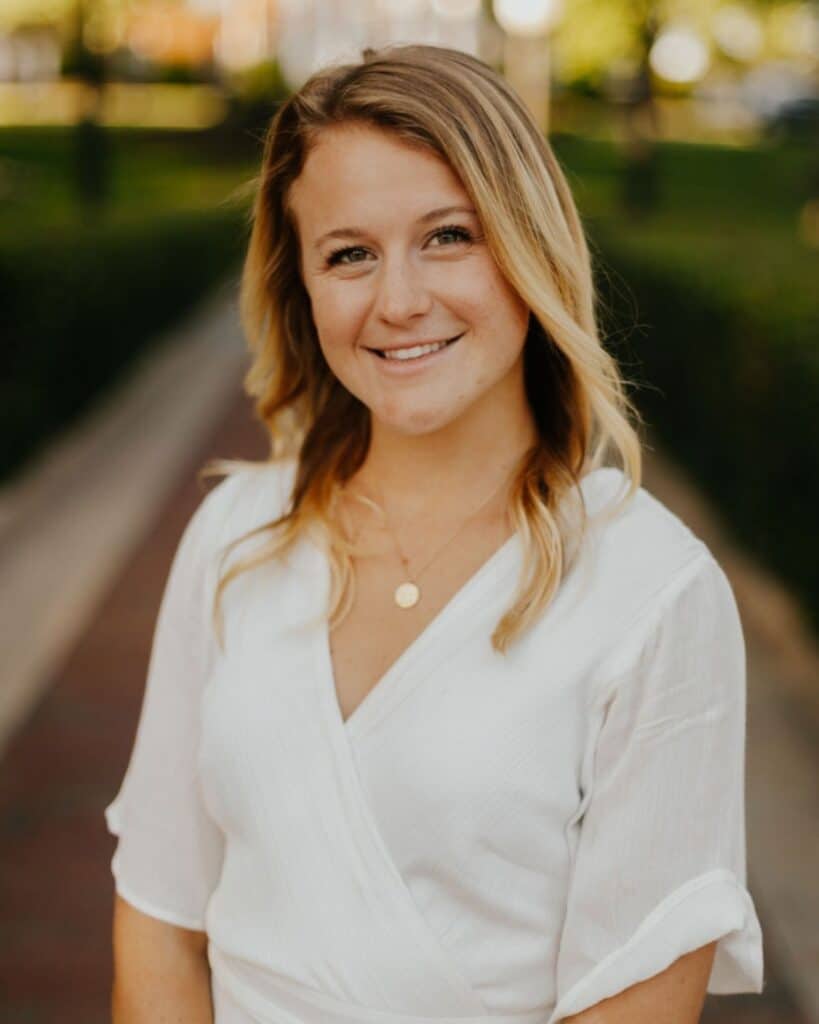 Photo of MINT Nutrition Registered Dietitian and Certified Personal Trainer, Lizzie. She is outside and wearing a white blouse.