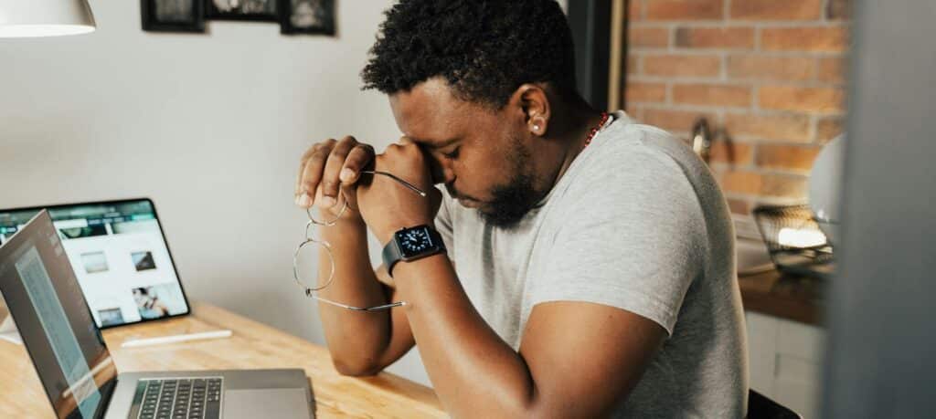 Man experiencing fatigue and brain fog at his desk, a common sign of hormone imbalance in men including low testosterone and high cortisol.
