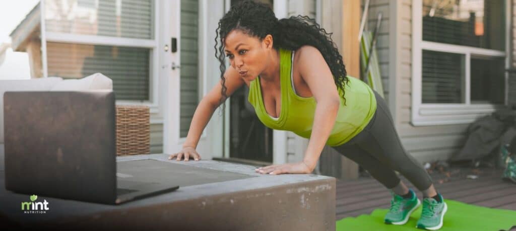 Woman exercising outdoors while following a workout on her laptop, representing an active lifestyle supported by hormone balance and integrative nutrition in Mooresville, NC.