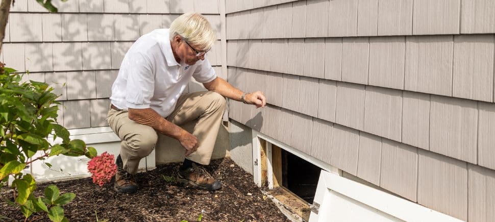 Home inspector checking a crawl space vent for moisture, a common source of the mold exposure that triggers CIRS.