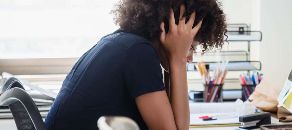 Woman at her desk with her head in her hands, showing the crushing fatigue and brain fog common with CIRS.