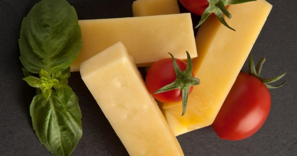 Aged parmesan cheese, a spermidine-rich food that supports autophagy, next to basil and cherry tomatoes